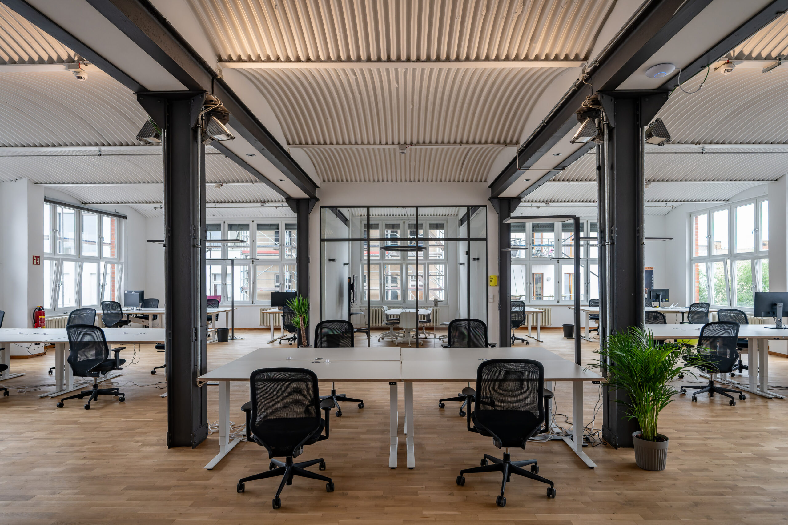 Modern open-plan office with industrial design and large windows.