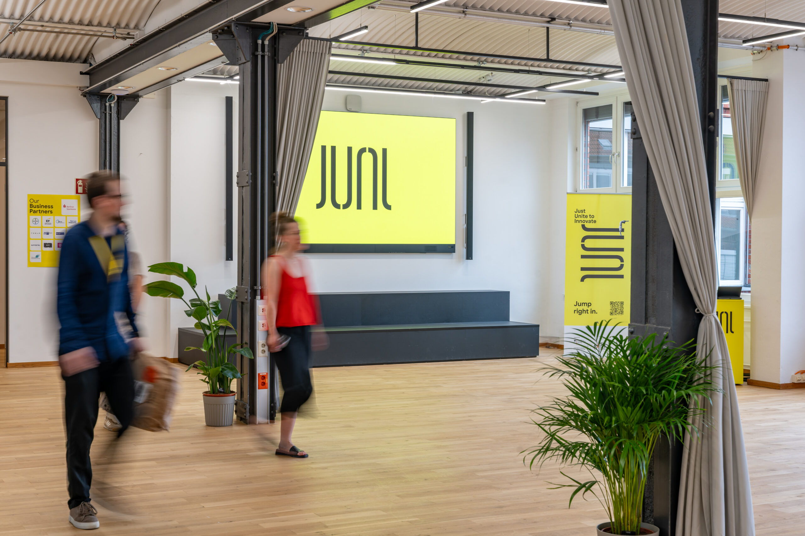 Modern industrial event space featuring yellow JUNI branding and signage.