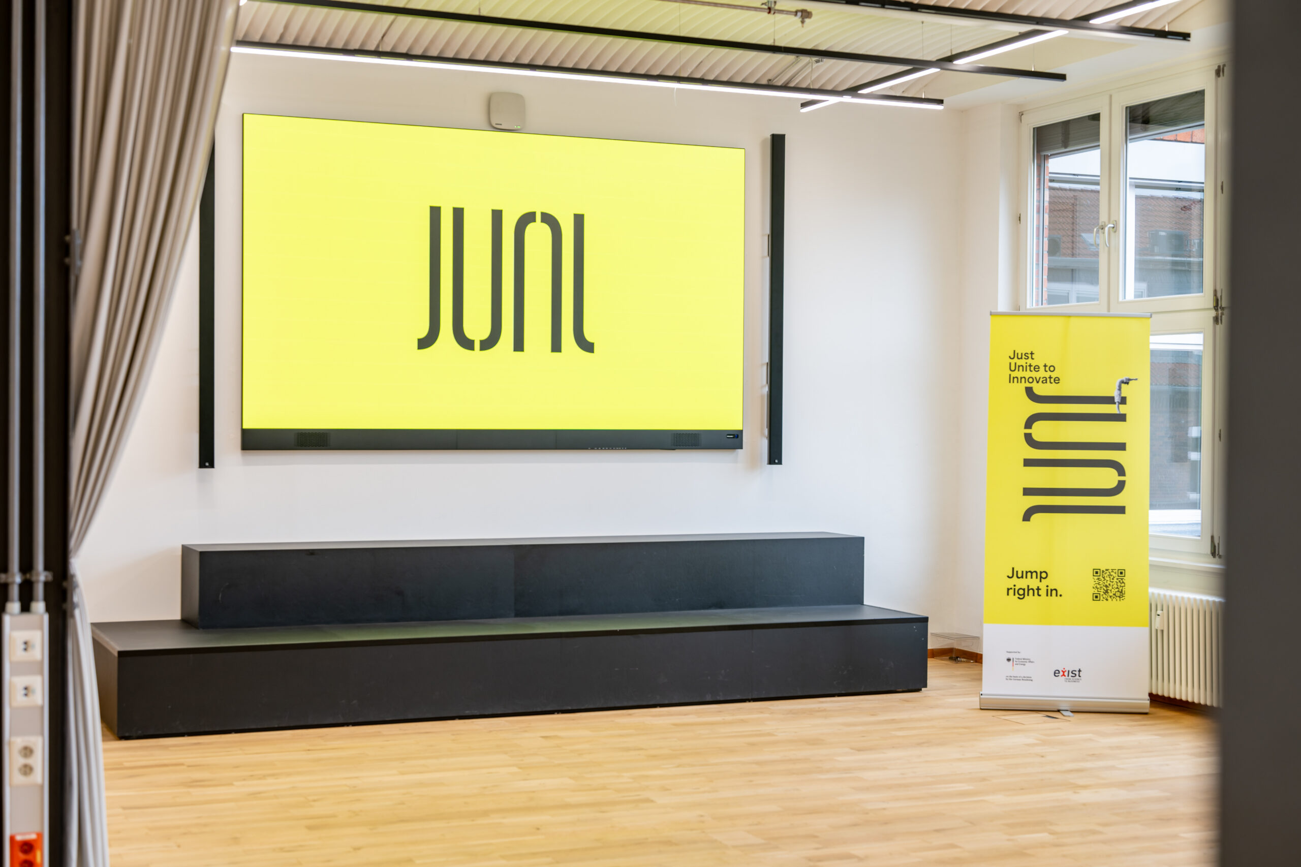 Large screen displaying JUNI logo in a modern office space.