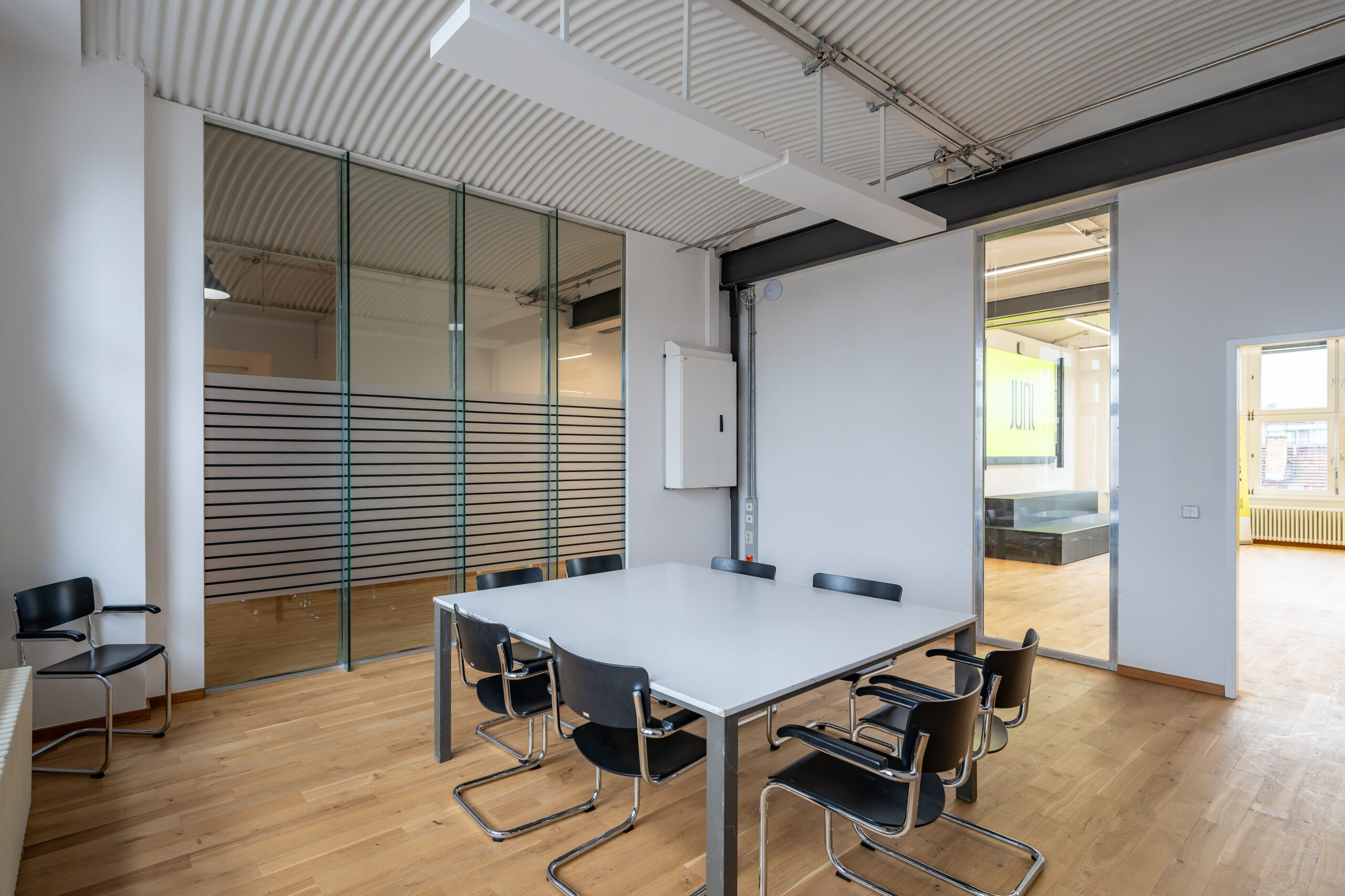 Modern meeting room with a white table and black chairs.