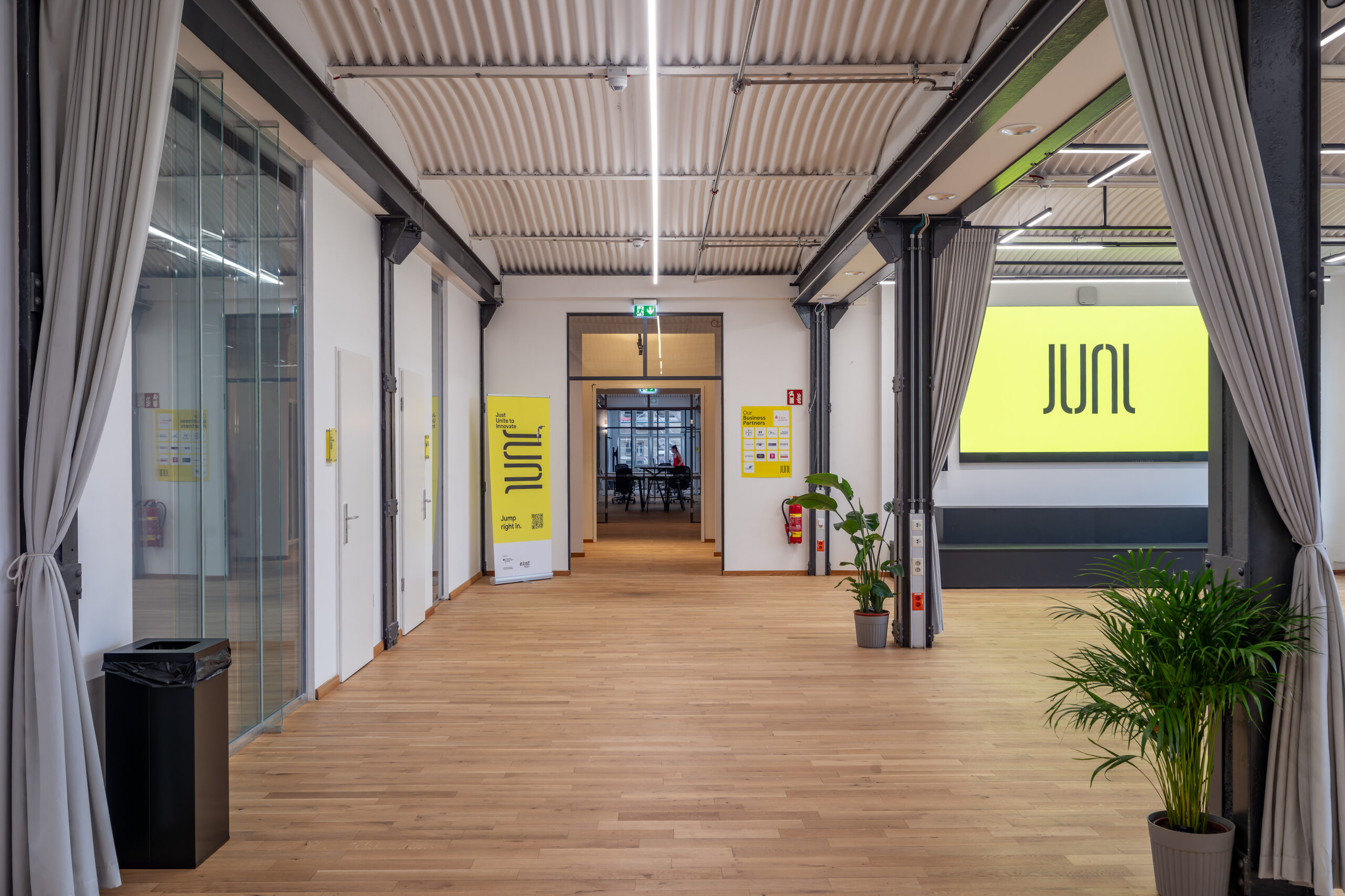 Modern industrial office interior with JUNI branding and wooden floors.