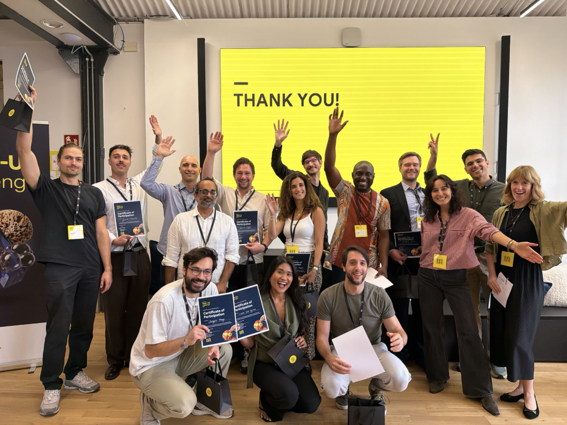 Diverse group holding certificates in front of a yellow screen.